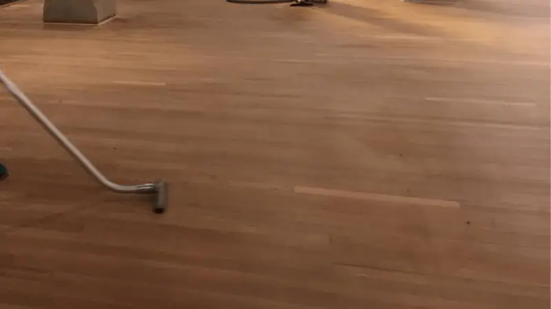vacuuming wooden floor to remove dust after polishing polyurethane with steel wool
