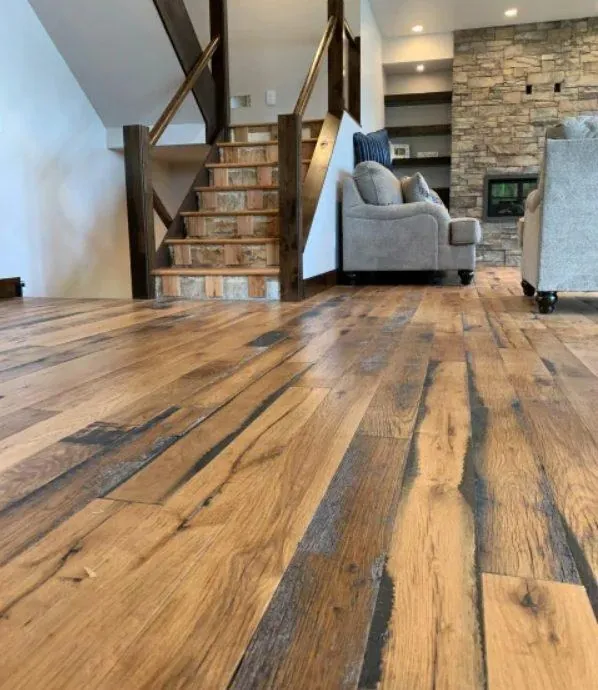 reclaimed wide plank oak flooring farmhouse living room with stone fireplace and wood staircase