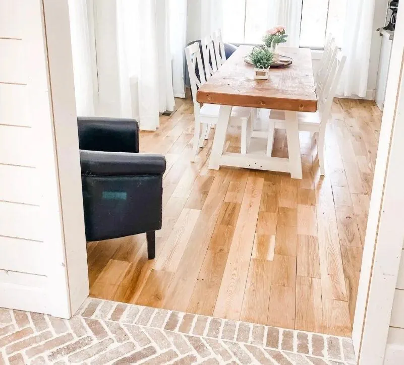 wide plank light oak hardwood flooring farmhouse dining room with white table and shiplap