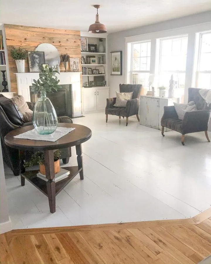 white painted wide plank wood floor farmhouse living room with shiplap accent wall and wood beam ceiling