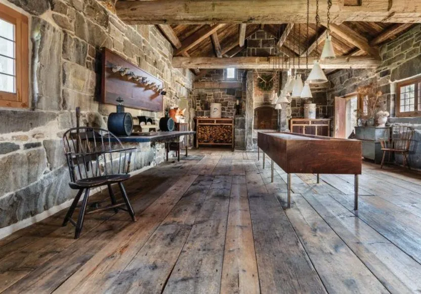 reclaimed barn wood wide plank flooring in rustic stone farmhouse room with exposed beams